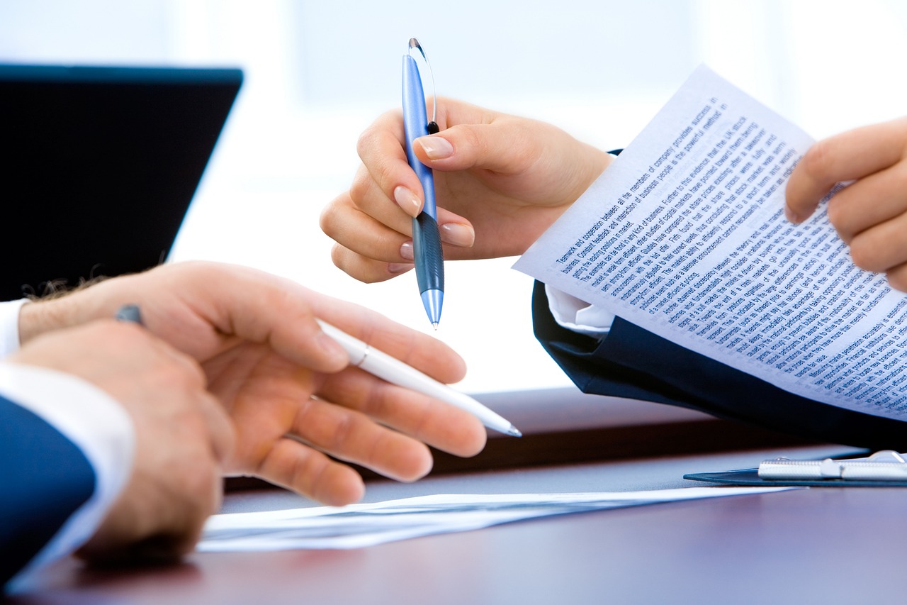 Writing on paper with laptop in office